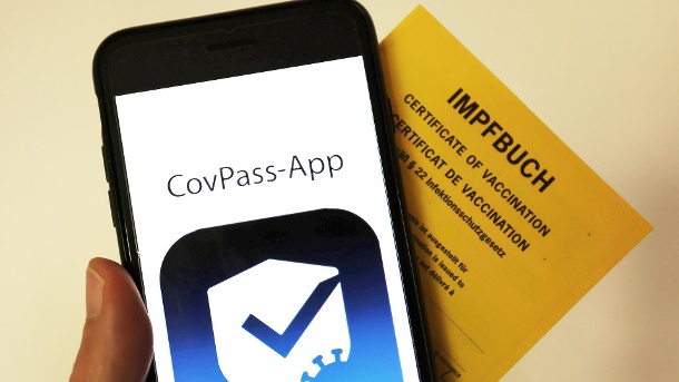 das-logo-der-covpass-app-ist-neben-einem-impfbuch-auf-einem-smartphone-der-digitale-corona-impfpass-in-deutschland-soll-an-diesem-donnerstag-starten-.jpg